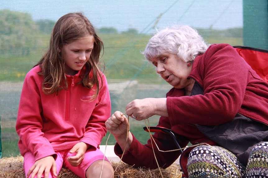 A girl is taught by an elder on  Mannalargenna Day.