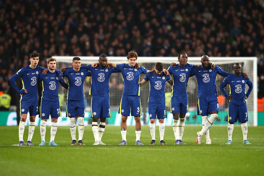 El equipo masculino del Chelsea se alinea cogidos del brazo para ver la tanda de penaltis contra el Liverpool
