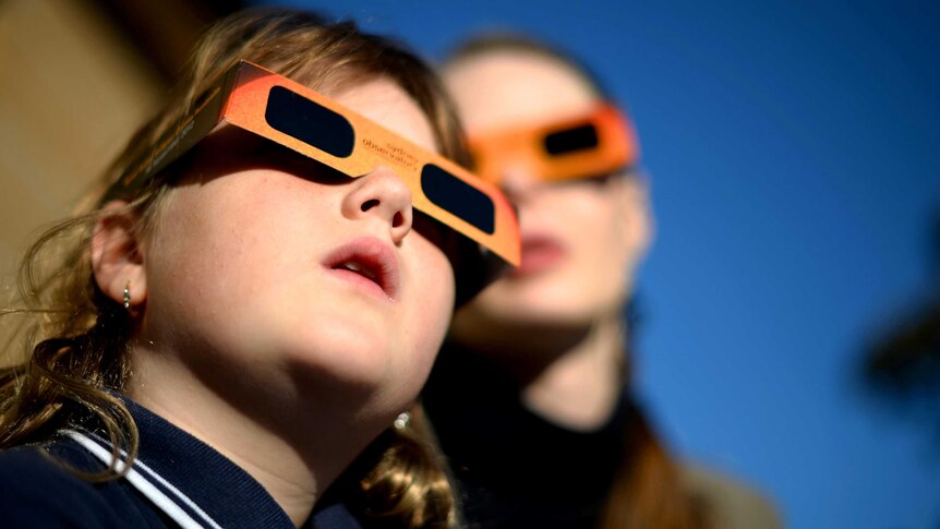 A child and a woman watch a partial annular eclipse.