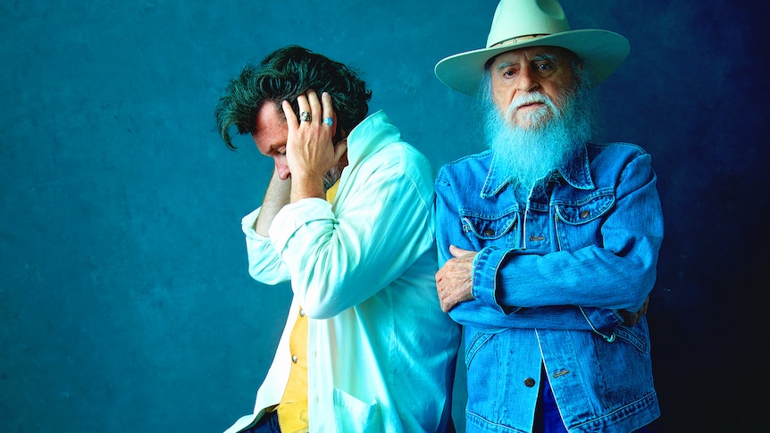 tommy mclain is wearing a blue denim jacket and wide brimmed hat and c.c. adcock is sitting with his hands on his ears