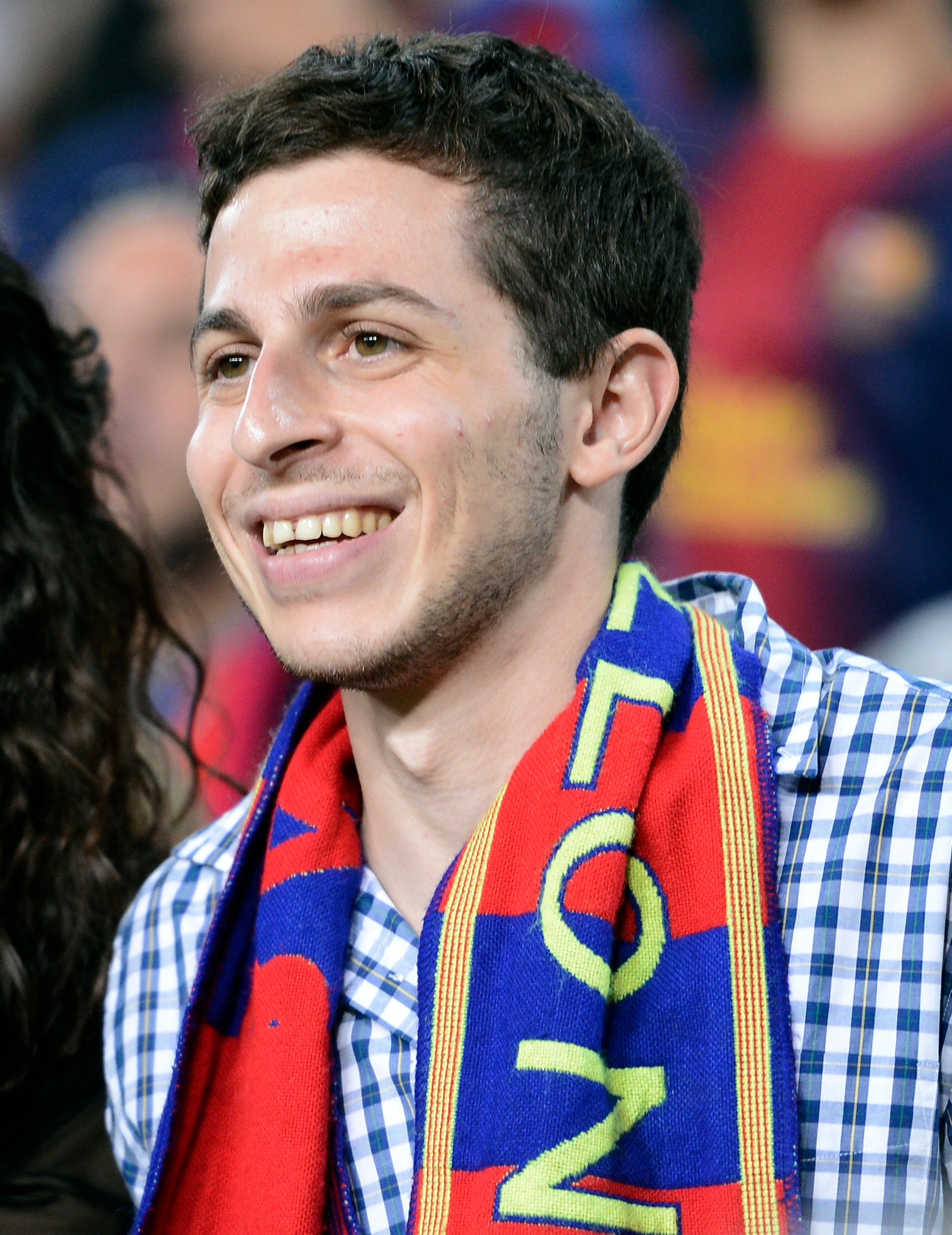 Man wearing blue and red checked scarf smiles 