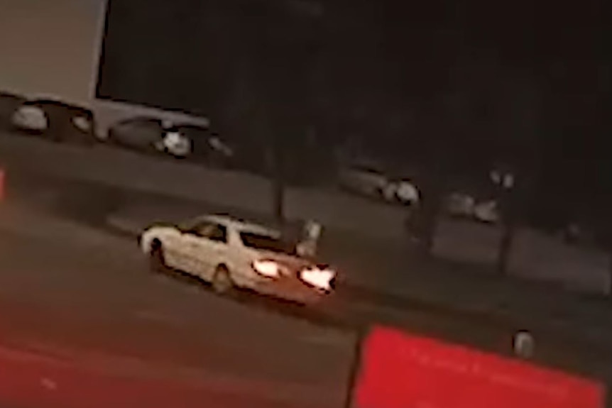 A white car turning a corner at night