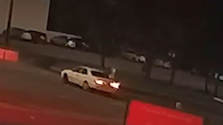 A white car turning a corner at night