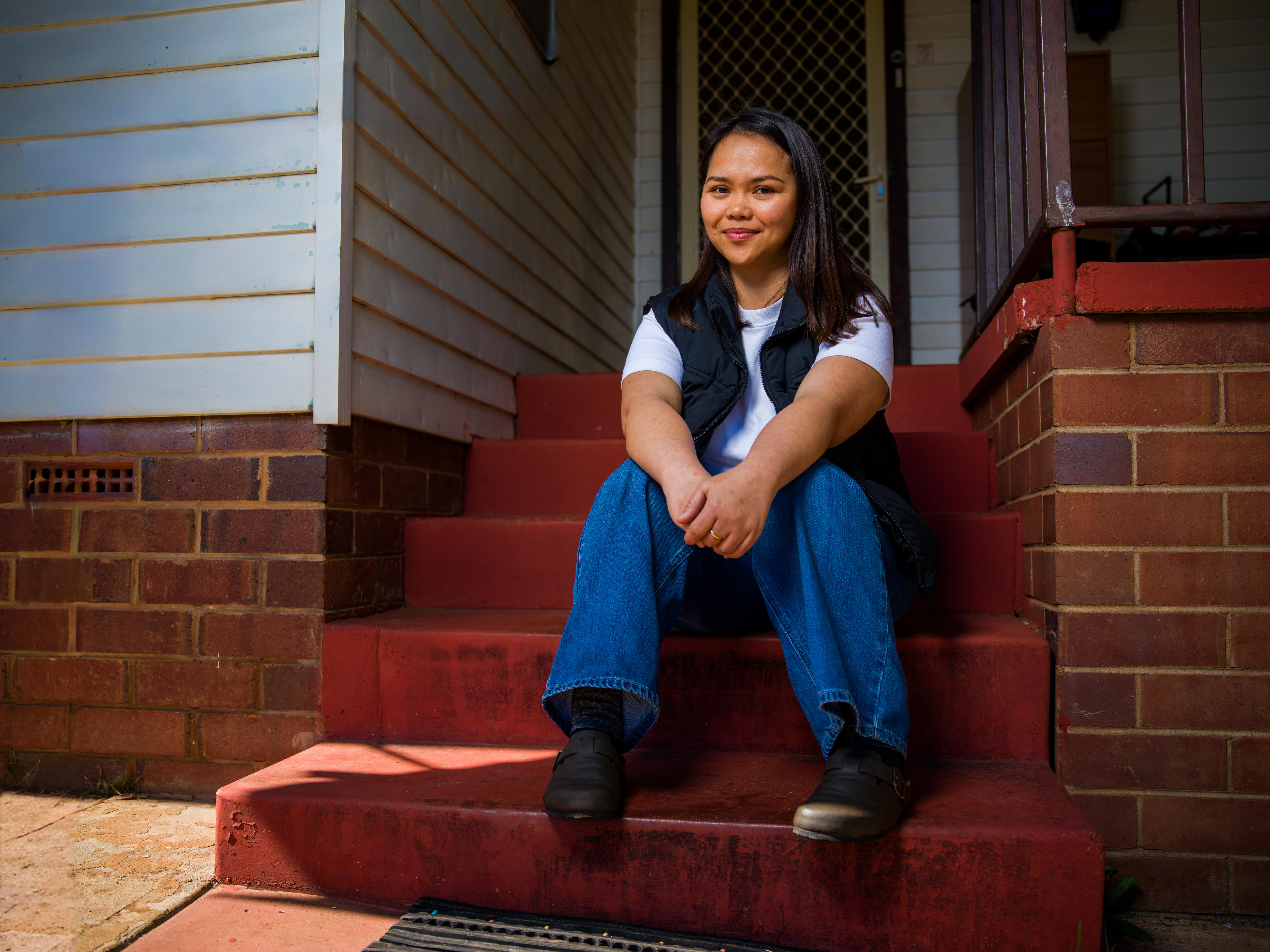 April sits by herself on the front step of her house in Coolamon.