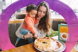 Mum with her toddler son in front of a pizza