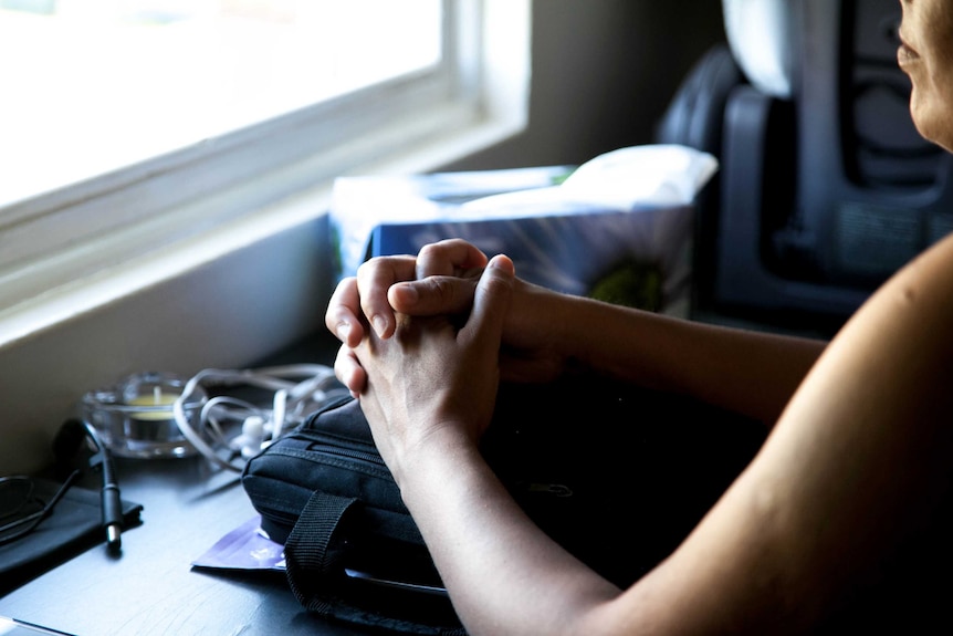 Close up of clasped hands resting on a table