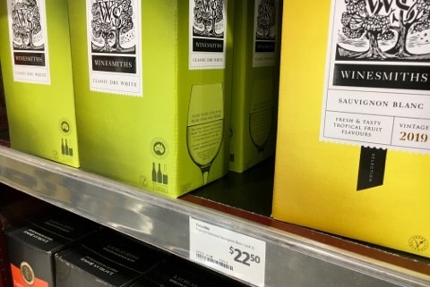A shelf with cask wine boxes on it and a price tag reading $22.50
