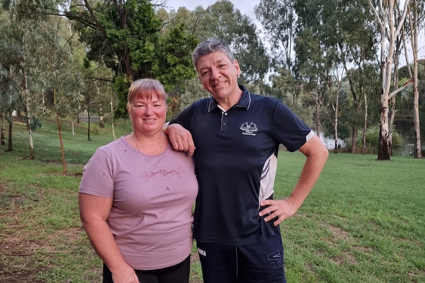 a woman and a man pose together in a green space