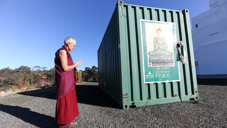 Resident nun and board member Tenzin Tsapel bows her head to the Jade Buddha inside the shipping container.
