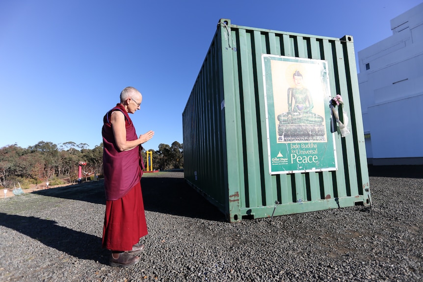 Resident nun and board member Tenzin Tsapel bows her head to the Jade Buddha inside the shipping container.