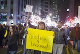 Protesters walk in the streets of Chicago carrying a sign saying "Justice for Laquan"