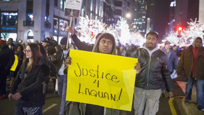 Protesters walk in the streets of Chicago carrying a sign saying "Justice for Laquan"