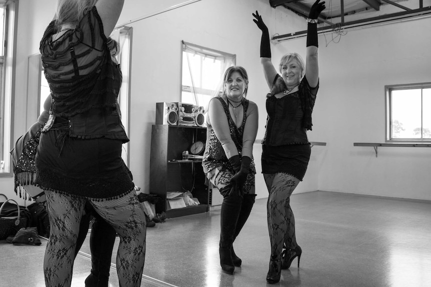 Miss Ruby Red and Miss Divine pose in the dance studio mirror