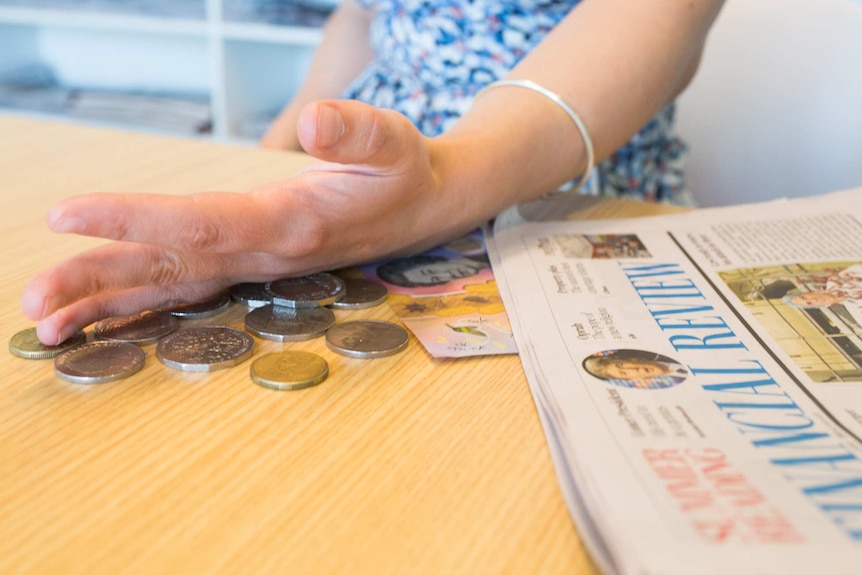 Woman's arm sweeping away money.