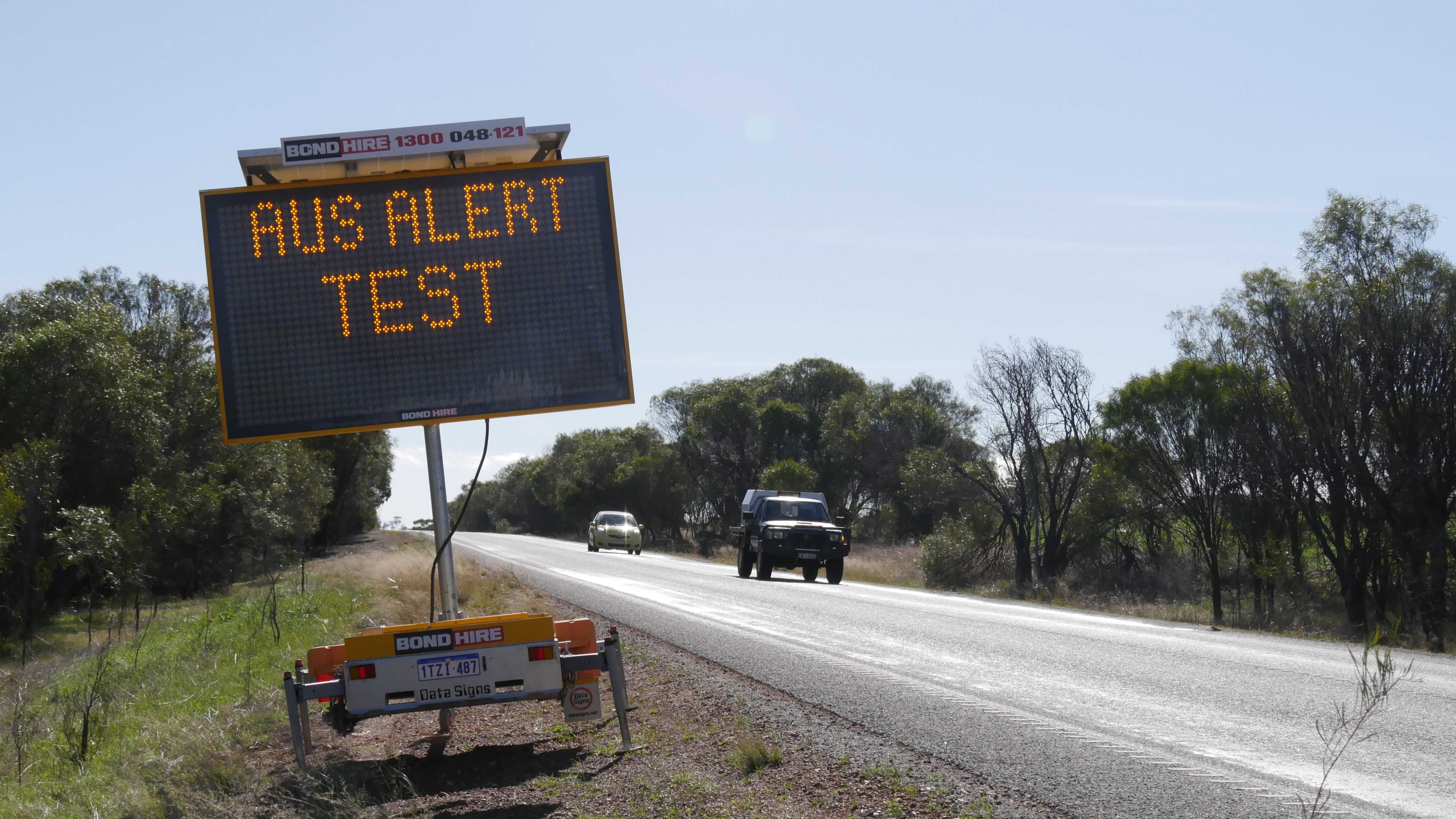 An electronic sign with the words 'AusAlert Test' next to a road.