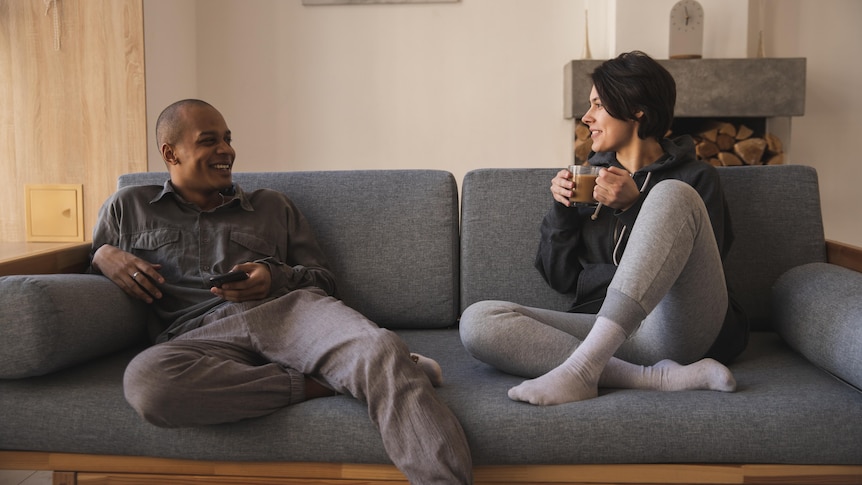 Man and woman sitting on couch chatting in a story about how men benefit from talking about their feelings