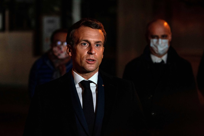 French President Emmanuel Macron speaks in front of a high school.