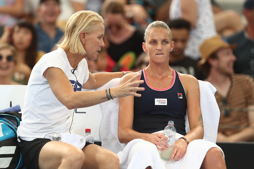 Rennae Stubbs speaks to Karolina Pliskova while sitting on the on-court chair during a tennis match.