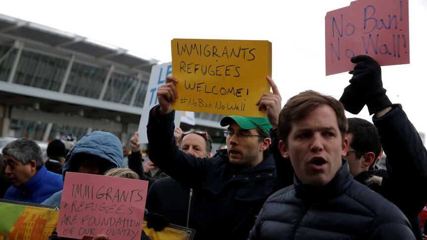 Protesters hold pro-refugee signs as they demonstrate outside the JFK International Airport in New York.