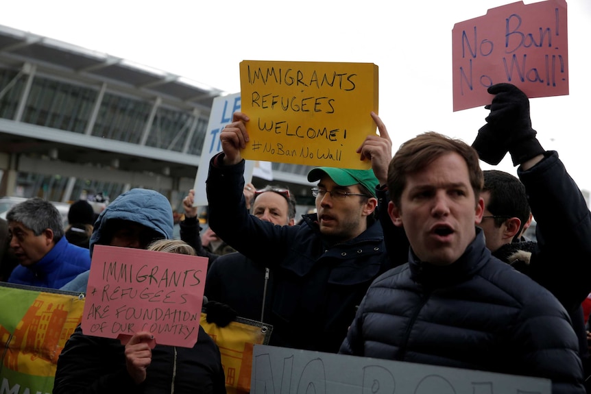Protesters hold pro-refugee signs as they demonstrate outside the JFK International Airport in New York.