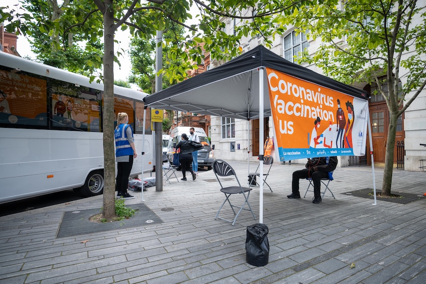 Health workers stand outside a mobile vaccination bus in London.