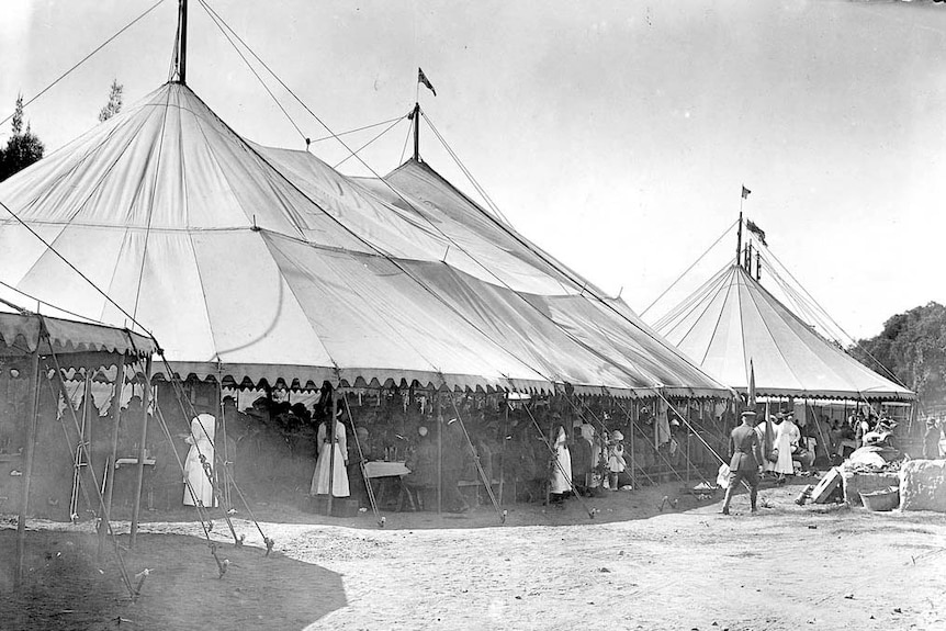An old photo showing large open tents with nurses and people crowding inside