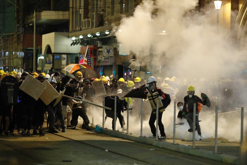Protesters react to teargas as they confront riot police officers in Hong Kong.