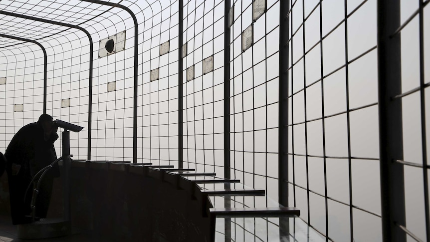 A visitor tries to see through the smog at a viewing deck in China.