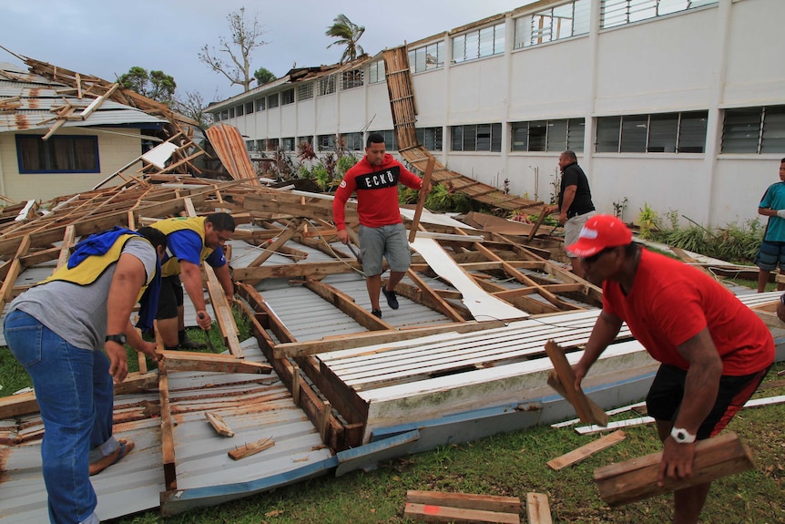 Wide shot of men cleaning up the debris of a roof.