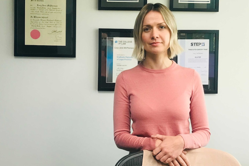 Senior associate at Attwood Marshall Lawyers Lucy McPherson stands in front of a wall of framed certificates