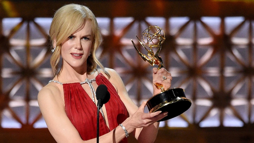 Nicole Kidman holds her Emmy in both hands and speaks into a microphone