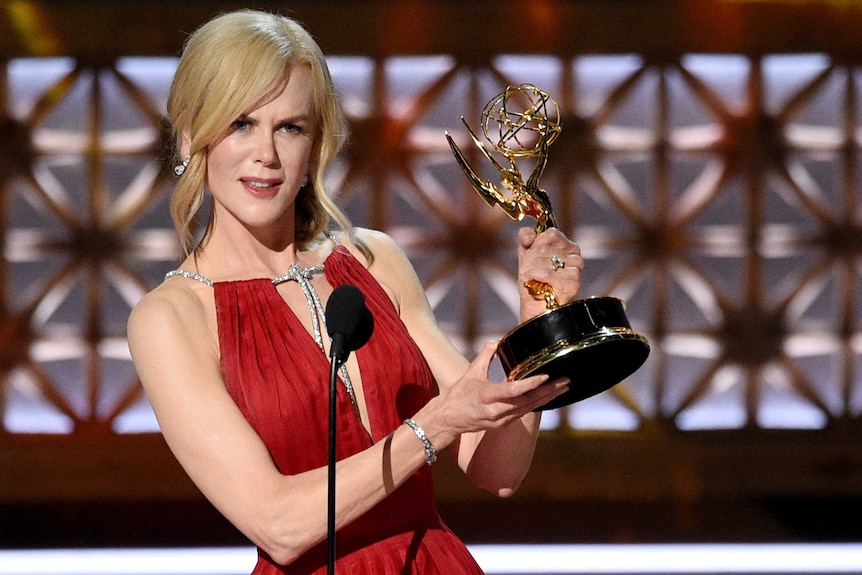 Nicole Kidman holds her Emmy in both hands and speaks into a microphone