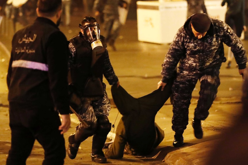 Two police officers drag a protester by his clothes