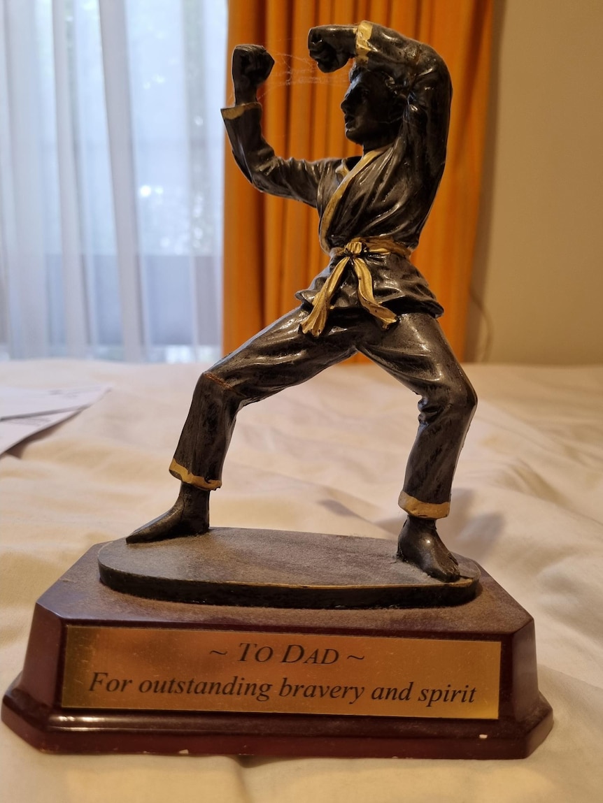 A bronze trophy with a man in a martial arts pose on top with the caption "to Dad for outstanding bravery and spirit".