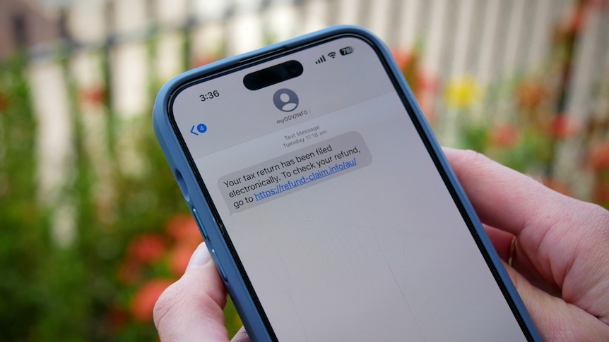 Hands hold a mobile phone displaying a scam text message