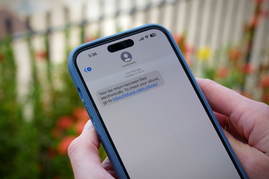 Hands hold a mobile phone displaying a scam text message