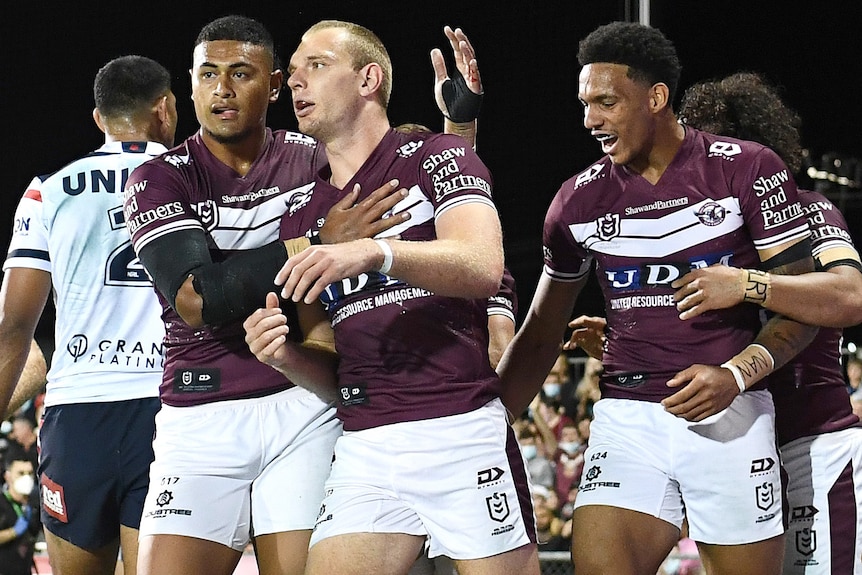 Four Manly NRL players celebrate a try being scored against the Sydney Roosters.