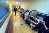 A hospital corridor with a row of gurneys along the side