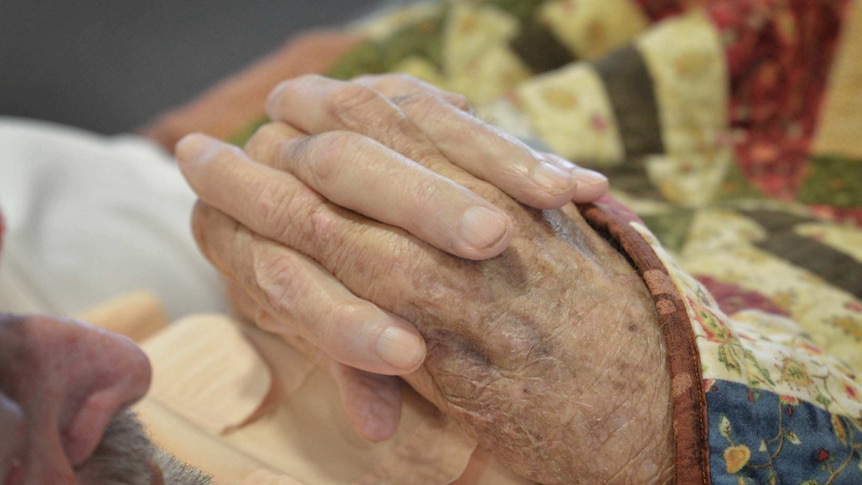 A close-up of wrinkled, knitted hands.