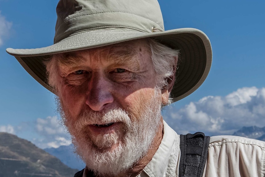 An older, bearded man wearing a broad-brimmed hat, squinting in the sun.