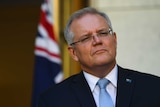 Morrison looks pensive in front of a flag