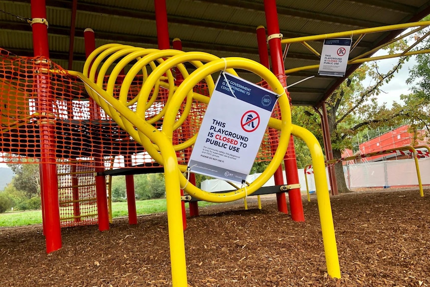 A sign stuck to an empty playground in Canberra's suburbs says it's closed