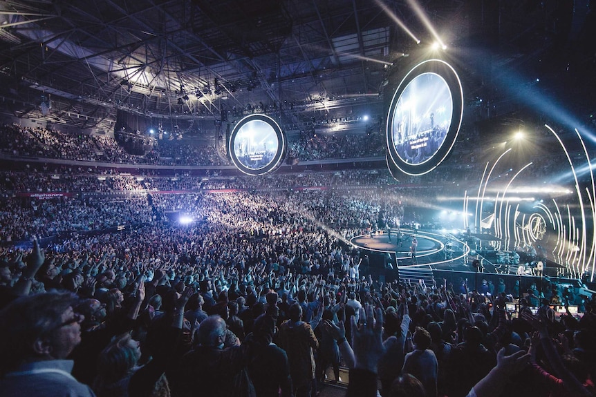 Lighting and music draw thousands of people for a Hillsong service.