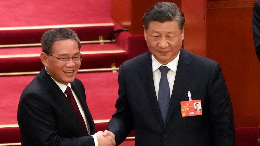Li Qiang (left) shakes hands with Xi Jinping.