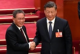 Li Qiang (left) shakes hands with Xi Jinping.
