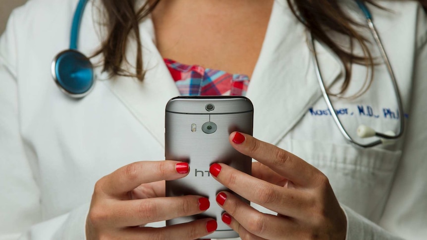 Female doctor wearing a stethoscope around her neck and holding a mobile phone