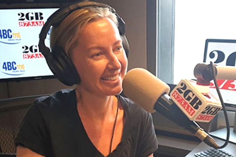 Deb Knight wearing headphones and smiling as she speaks into a radio studio microphone