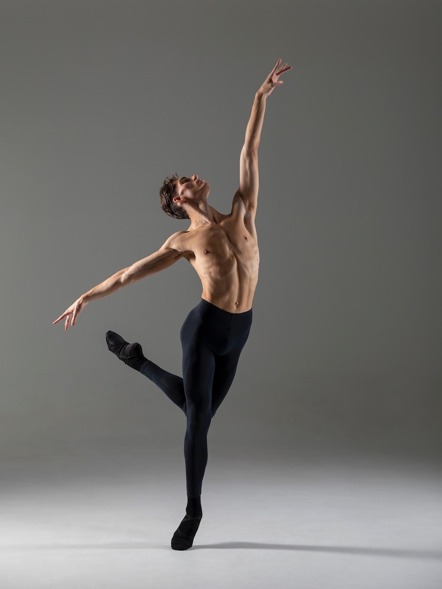 A young man in ballet tights in full stretch as he dances ballet.