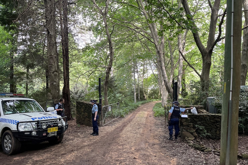 police stand out the front of a rural property