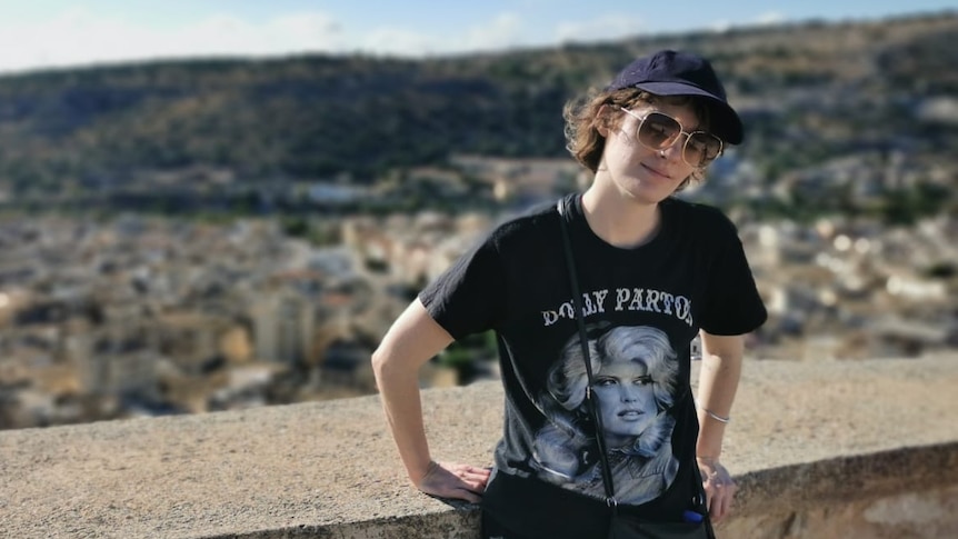 Ruby McGrath-Lester on holiday in Sicily, standing in front of a mountain view